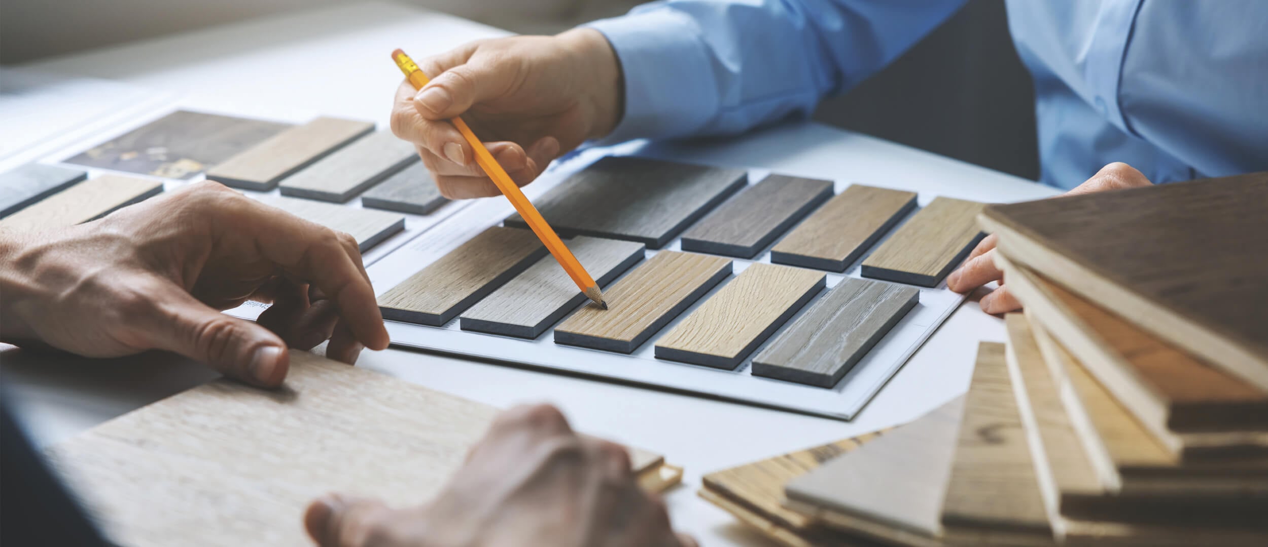 Hands comparing wood flooring samples at an Ogden's showroom table