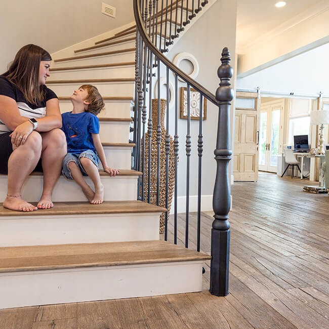 a mother and son sitting on stares with beautiful hardwood flooring