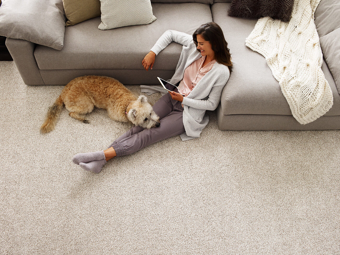 woman and dog sitting on carpet flooring in living area