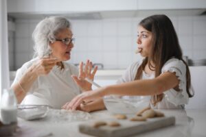 Grandmother and granddaughter in kitchen having fun. 