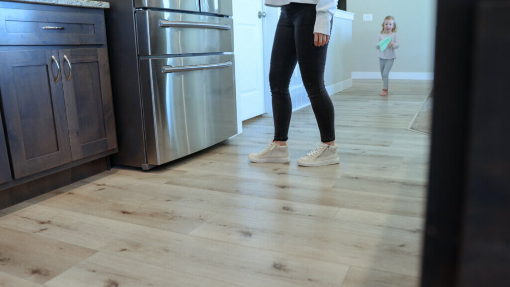 Woman opening fridge in kitchen standing on luxury vinyl plank flooring